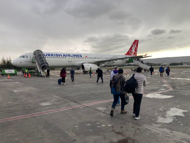 Foto: Menschen mit Taschen und Gepäck gehen zu einem Flugzeug
